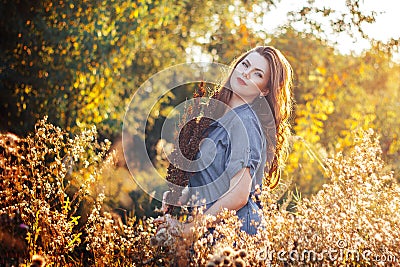 Young woman with a flowers in autumn field Stock Photo