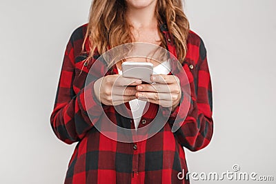 Freestyle. Young woman with freckles standing isolated on grey playing on smartphone close-up blurred background Stock Photo