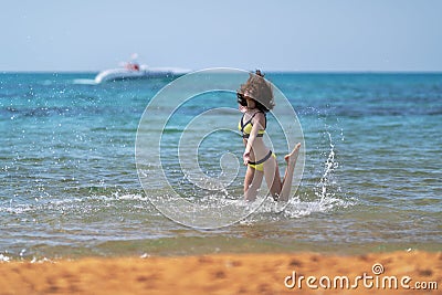 Young woman frolicking in the sea on a sandy beach Stock Photo