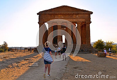 20.08.2018. Young woman in front of Ruined Temple Concordia on hill and tourists in famous ancient Valley of Temples, Agrigento, S Editorial Stock Photo