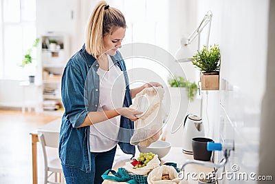 Young woman with fruit in reusable bag indoors, sustainable lifestyle. Stock Photo