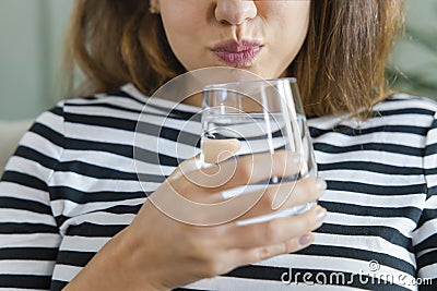 Young woman gargling with a glass of water Stock Photo