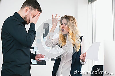 Young woman general manager angry with man manager for unproper documents preparation before important deal in her modern bright Stock Photo