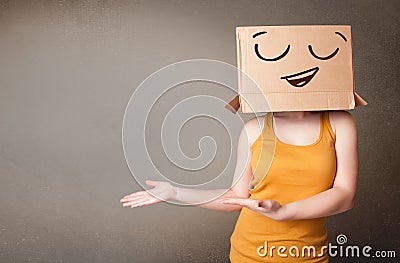 Young woman gesturing with a cardboard box on her head with smiley face Stock Photo