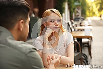 Young woman getting bored during first date with man at cafe Stock Photo