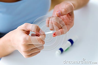 Young woman getting glucose test with glucometer at home. Incorrect process concept. Stock Photo