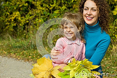 Young woman and girl laugh with leaves in garden Stock Photo