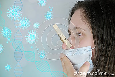 Young woman, a girl in a white medical mask with long blond hair, her nose is clamped with a wooden clothespin, the concept stinks Stock Photo