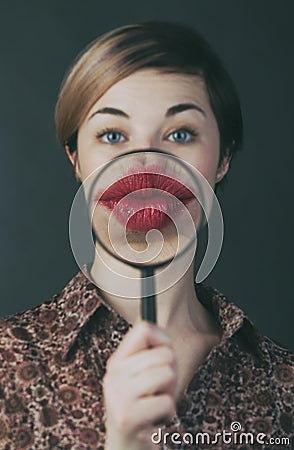 Young woman give kiss through a magnifying glass Stock Photo