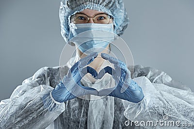 Young woman in glasses with a medical mask and hands in latex glove shows the symbol of the heart Stock Photo