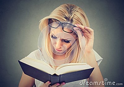Young woman with glasses suffering from eyestrain after reading a book Stock Photo