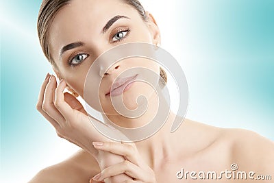 Young woman with glowing skin posing at isolated light blue background Stock Photo