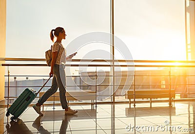 Young woman goes at airport at window with suitcase waiting for Stock Photo