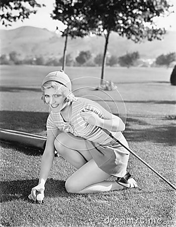 Young woman on a golf course placing a golf ball Stock Photo