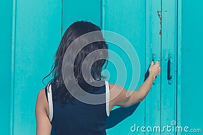 Young woman grabbing blue door Stock Photo