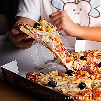 Young woman grabbing a slice of pizza Stock Photo