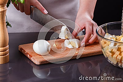 Young woman in a gray apron cuts a boiled egg Stock Photo