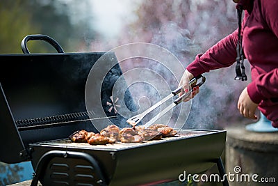 Young woman grills some kind of marinated meat and vegetable on gas grill during summer time, BBQ Stock Photo