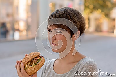 Young woman grimacing in distaste at a burger Stock Photo