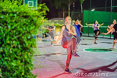 Young woman on a group workout on the basketball court in the evening Stock Photo