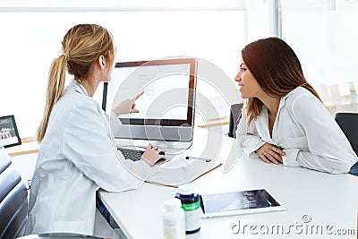 Young woman gynecologist doctor showing to patient some information in computer in medical consultation Stock Photo