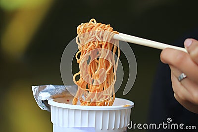 Young woman hand holding plastic fork of instant noodles, Sodium diet high risk kidney failure, Healthy Eating Stock Photo