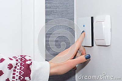 Smart Home Convenience: Young Woman Controlling Light with Touch Switch Stock Photo