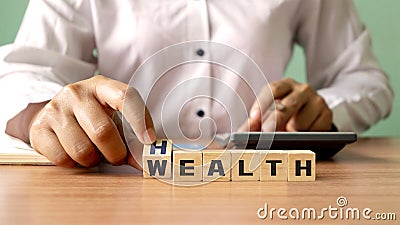 Young woman hand turning wooden dice with wealth and health, financial wealth concept. Stock Photo