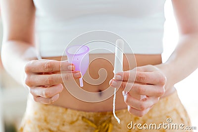 Young woman hands holding different types of feminine hygiene products - menstrual cup and tampons. Stock Photo