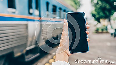 Young woman hands holding mobile at railway station for searching hotel room for booking and payment by internet cashless Stock Photo