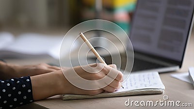 Young woman hands making notes in copybook by computer screen Stock Photo