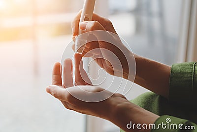 Young woman hands using glucometer on finger at home to check blood sugar level Stock Photo