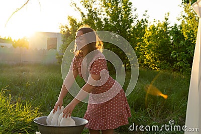 Young woman hanging laundry outdoors. Beautiful girl in red polkadot dress Stock Photo