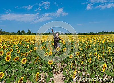 Young woman happily jumping in a field of sunflower Stock Photo