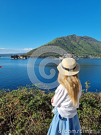 Young woman in hat stands on the coastline in Montenegro Saint George Island in Kotor Bay Boka Kotorska near Perast city Stock Photo