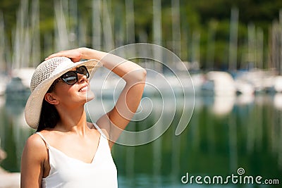 Young woman with hat summer dress and sunglasses walks pier of m Stock Photo