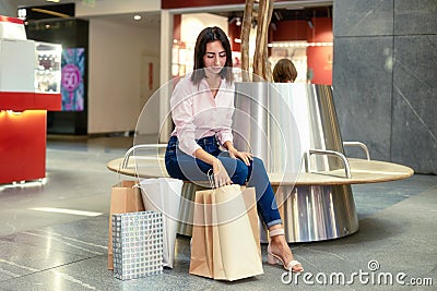Young woman have a rest after shopping in the mall with shopping bags or packages. Fashion, clothing, sale, discount, black friday Stock Photo