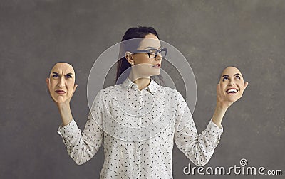 Young woman having bipolar disorder holding two face masks with opposite emotions Stock Photo