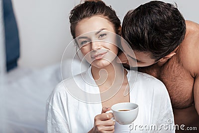 Young woman having coffee with boyfriend in bed Stock Photo