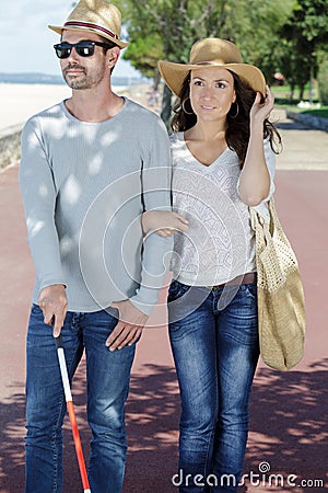 Young woman helping blind man with white stick Stock Photo