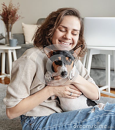 Young woman hugging her cute basenji dog at home. Love and care pet Stock Photo