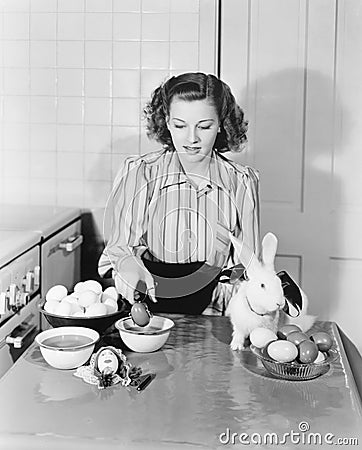 Young woman in her kitchen coloring Easter eggs Stock Photo