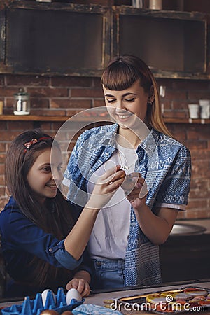 Young woman with her little sister cracking Easter eggs Stock Photo