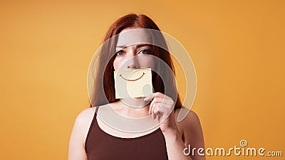 young woman hiding emotion with fake smile drawn on paper Stock Photo