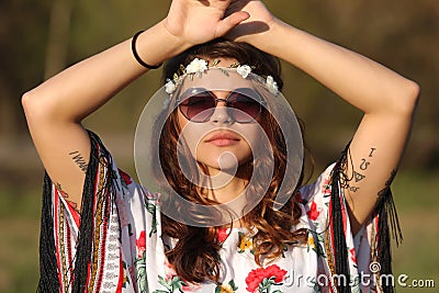 Young woman in hippie style looking at the camera and holding hands on head Outdoors Stock Photo