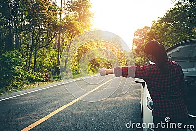 Young woman hitchhike for help while at broken car on road Stock Photo