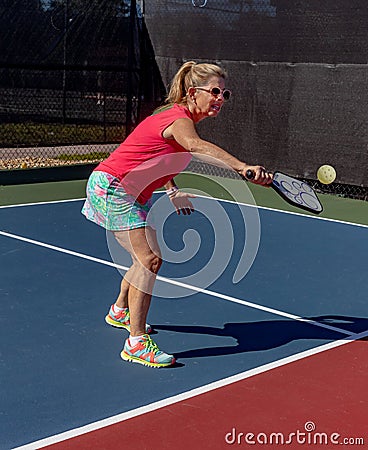 Young woman hits a pickleball with a backhand volley Stock Photo