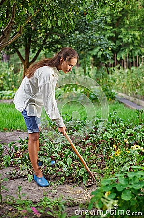 Young woman with hoe working in the garden bed Stock Photo