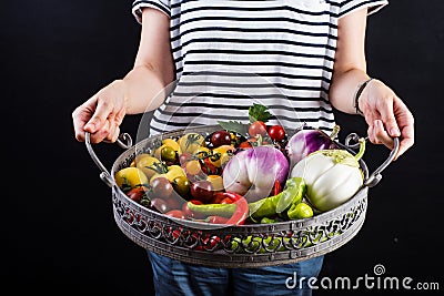 Young woman holding a basket full of veggies Stock Photo