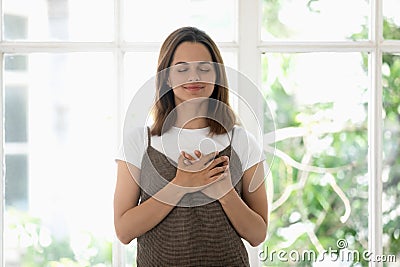 Young woman holding both hands on heart symbol of gratitude Stock Photo